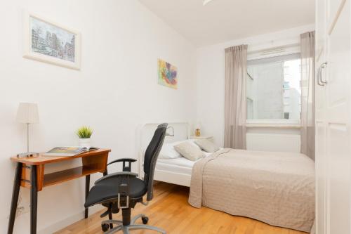 a bedroom with a bed and a desk and a chair at Fort Bema Apartment with Parking by Renters in Warsaw
