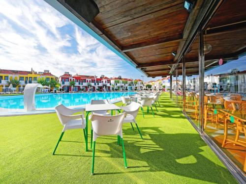 a patio with tables and chairs next to a swimming pool at Bungalows Vistaflor in Maspalomas