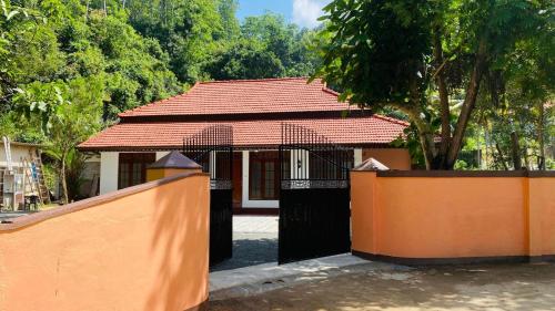 a small house with a red roof and a fence at RED ROSE HOLIDAY HOUSE in Matara