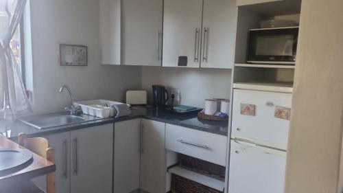 a kitchen with white cabinets and a sink and a microwave at Bluewater Reservations in Port Elizabeth