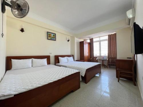 クアローにあるChâu Giang Hotel Cửa Lòのベッド2台とテレビが備わるホテルルームです。