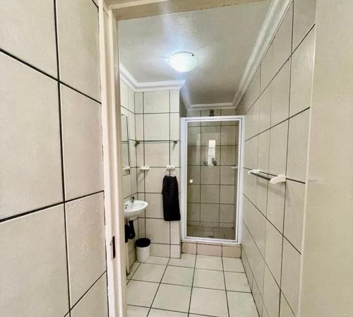 uma casa de banho com um chuveiro e um lavatório. em The Eden Boulders Hotel and Resort Midrand em Midrand