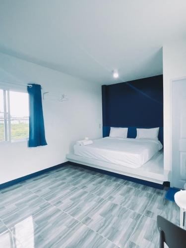 a bedroom with a white bed with a blue headboard at TJ Garden & Resort in Ban Dan Chang