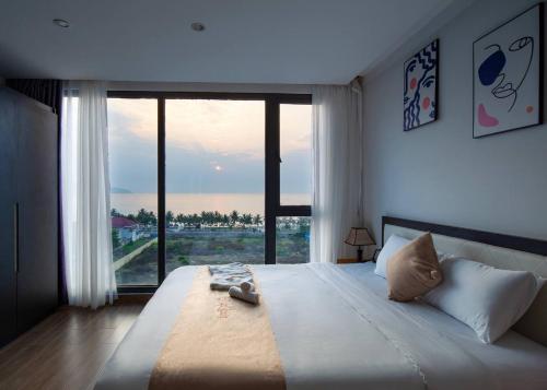 a bedroom with a large bed with a large window at KIKOZO DA NANG Hotel in Da Nang
