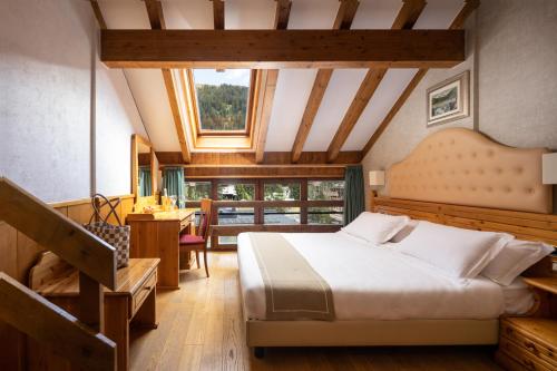 um quarto com uma cama, uma secretária e uma mesa em Hotel Splendid em Madonna di Campiglio