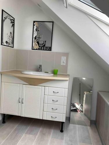 une salle de bain avec un lavabo et un escalier avec un miroir dans l'établissement Appartement dans maison de campagne au calme, à La Trinité-sur-Mer