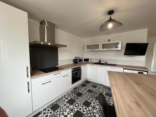 a kitchen with white cabinets and a wooden table at Coeur de ville , 70m2 , 2 chambres in Saint-Brieuc