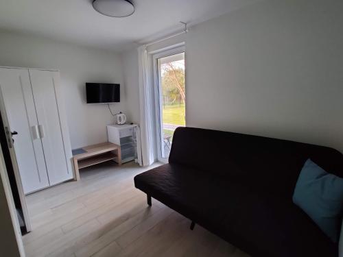 a living room with a black couch and a window at Ostrowo Plaza in Ostrowo