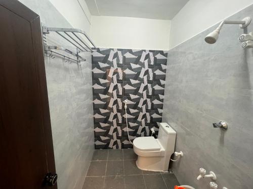 een badkamer met een toilet en een zwart-witte muur met patronen bij David Residency in Madurai