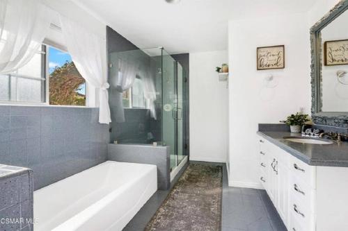 y baño con bañera, ducha y lavamanos. en 4 bed 3 bath pool house gated property, en Thousand Oaks