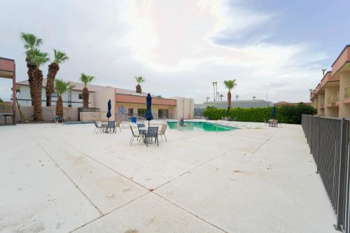 a patio with chairs and a swimming pool with palm trees at Royal Plaza Inn in Indio