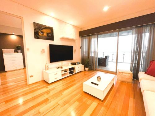 a living room with a white couch and a flat screen tv at 47 Breathtaking City Riverviews 2brpark in Perth