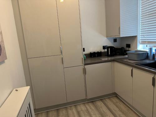 uma cozinha com armários brancos e um frigorífico em A place of Rest em Middlesbrough