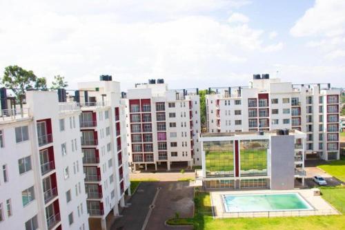 ナイロビにあるRacecourse Studio Apartmentsの中央にスイミングプールがあるアパートメントビル