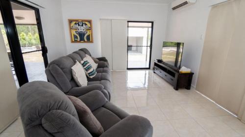 a living room with two chairs and a flat screen tv at Tiramula Lodge Holiday House in Horseshoe Bay