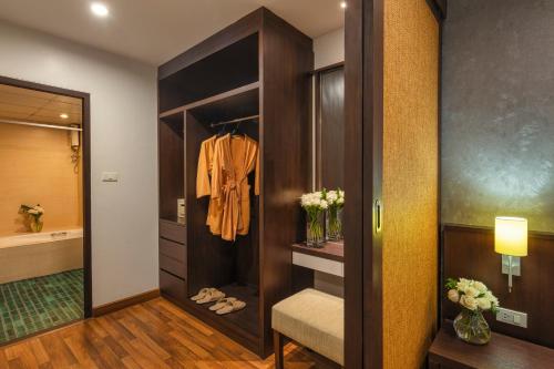 a bathroom with a walk in closet with a robe at The Grand Napat in Chiang Mai
