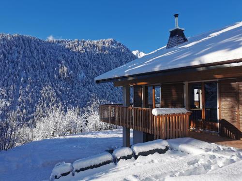 uma cabana de madeira com neve no alpendre em Chalet Domisiladoré - chalet haut de gamme pour 10 adultes et 2 enfants à Châtel em Châtel