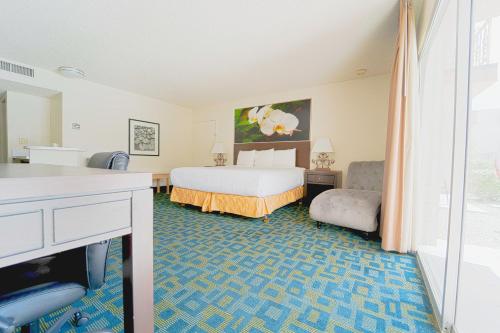 a hotel room with a bed and a desk and a window at Royal Plaza Inn in Indio
