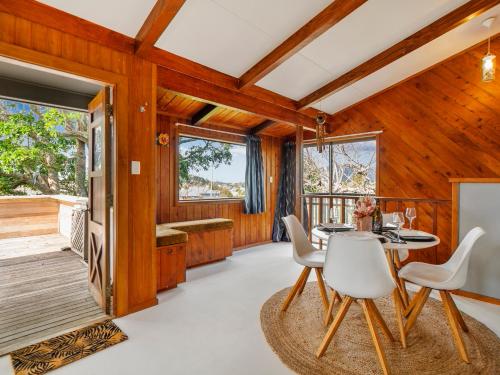 a dining room with a table and chairs and wooden walls at Paku View Retreat - Tairua Holiday Home in Tairua