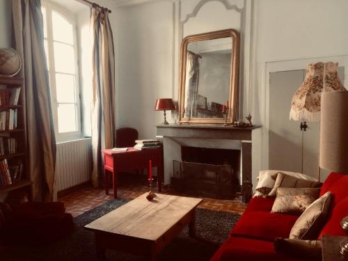 a living room with a red couch and a mirror at SAUVEURS DE REVES 2 suites indépendantes et un F2 privé dans un hôtel particulier in Sauve