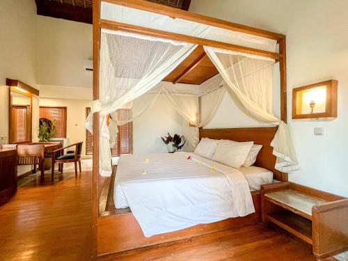 een slaapkamer met een groot wit bed en een baldakijn bij The Lagoon Bali Pool Hotel and Suites in Legian