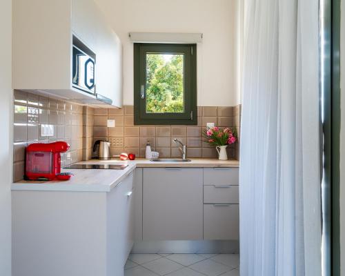 a kitchen with white cabinets and a window at Blue View Villas in Stalida