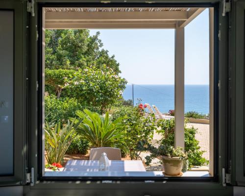 a window view of the ocean from a patio at Blue View Villas in Stalida