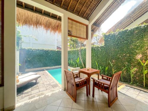 a patio with a table and chairs and a pool at The Lagoon Bali Pool Hotel and Suites in Legian