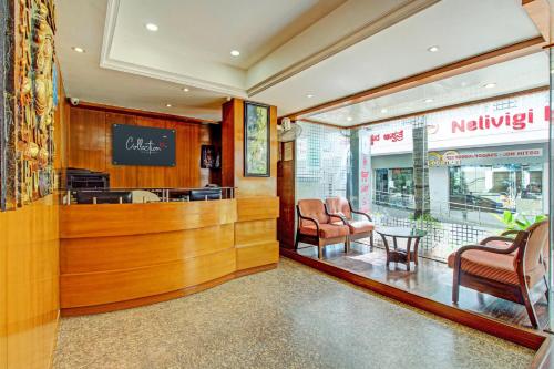 a restaurant with a waiting area with chairs and a table at Capital O Sri Krishna Suites Near 7d Voyage in Bangalore