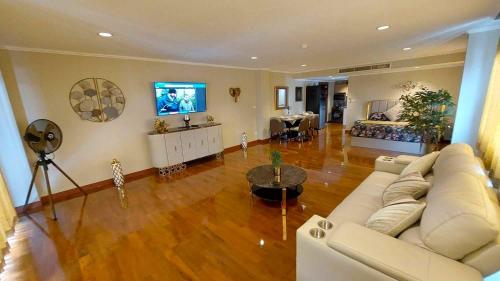 a living room with a white couch and a television at Beachfront Apartment with Balcony, Sea View & Pool View - Cha Am - Hua Hin in Ban Pak Khlong Cha-am