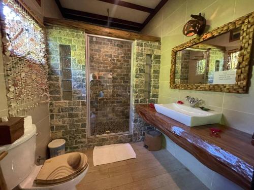 a bathroom with a sink and a toilet and a mirror at La Digue Holiday Villa in La Digue