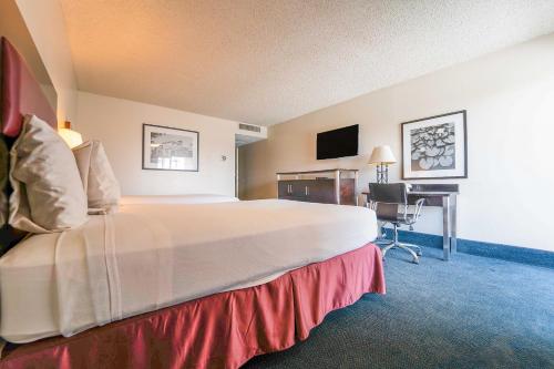 a hotel room with a large bed and a desk at Royal Plaza Inn in Indio