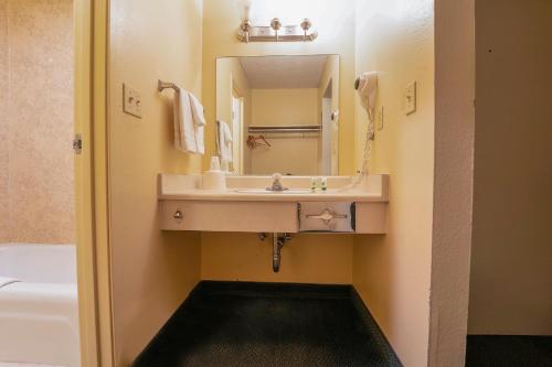 a bathroom with a sink and a mirror and a tub at Royal Plaza Inn in Indio
