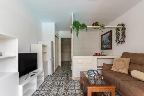 ein Wohnzimmer mit einem Sofa und einem TV in der Unterkunft Home2Book Charming Studio Playa del Inglés in San Bartolomé de Tirajana