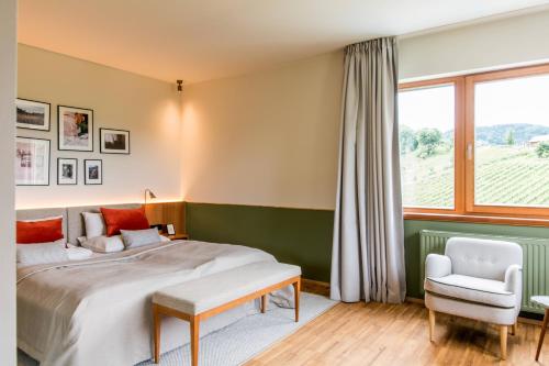 ein Schlafzimmer mit einem Bett, einem Stuhl und einem Fenster in der Unterkunft Landgut am Pößnitzberg in Leutschach
