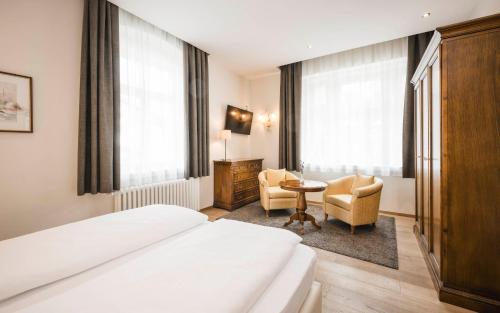 a hotel room with a bed and a table and chairs at Hotel Villa Kastelruth in Castelrotto