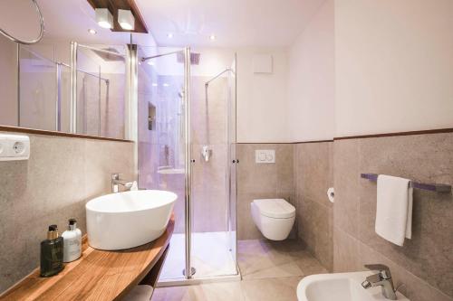 a bathroom with a sink and a shower and a toilet at Hotel Villa Kastelruth in Castelrotto