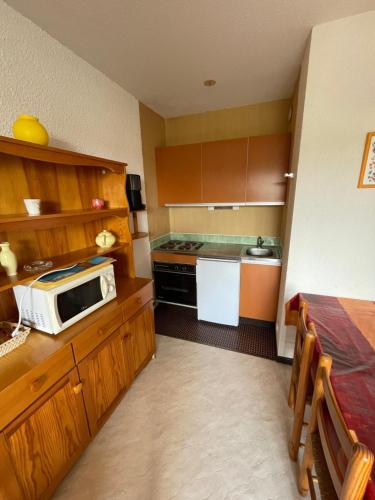 a small kitchen with a microwave on a counter at Réf 413 Seignosse océan, studio alcôve à proximité immédiate de la plage et des commerces, 4 personnes in Seignosse