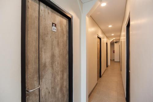 a corridor with a wooden door in a hallway at RedDoorz Plus at Eskole ITERA Lampung in Lampung