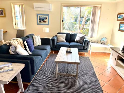 a living room with a blue couch and a table at Villa Asteri, Hawk's Nest: Walk to everything! in Hawks Nest