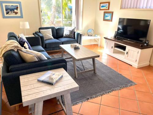 a living room with a couch and a tv at Villa Asteri, Hawk's Nest: Walk to everything! in Hawks Nest