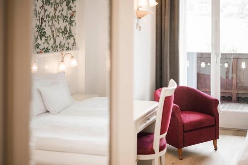 a room with a bed and a desk and a chair at Hotel Villa Kastelruth in Castelrotto
