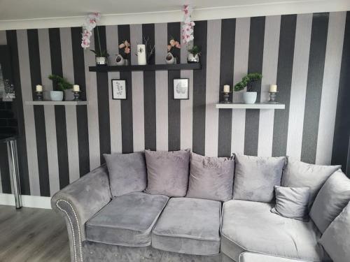 a living room with a gray couch and striped wall at Sanity Sanctuary in Leysdown-on-Sea