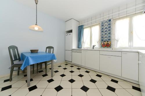 une cuisine avec une table et des chaises et une cuisine avec des placards blancs dans l'établissement Haus Traumstraße, à Witsum