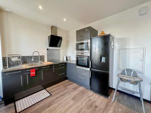 une cuisine équipée d'appareils électroménagers en acier inoxydable et d'un réfrigérateur noir. dans l'établissement Superbe appartement T3 cosy de 60m2, à Brest