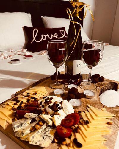 a tray of food and two glasses of wine on a bed at Wild nest Deer Lux in Zlatibor