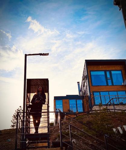 a woman sitting on a stairs in front of a building at Wild nest Deer Lux in Zlatibor