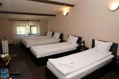 2 camas en una habitación de hotel con sábanas blancas en Опълченец, en Shipka