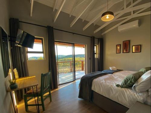a bedroom with a bed and a table and a window at Khululeka Safaris Lodge in White River