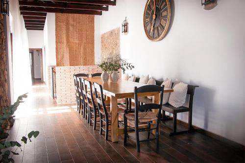 mesa de comedor con sillas y reloj en la pared en Cortijo Rural Alcornocosas, en Córdoba